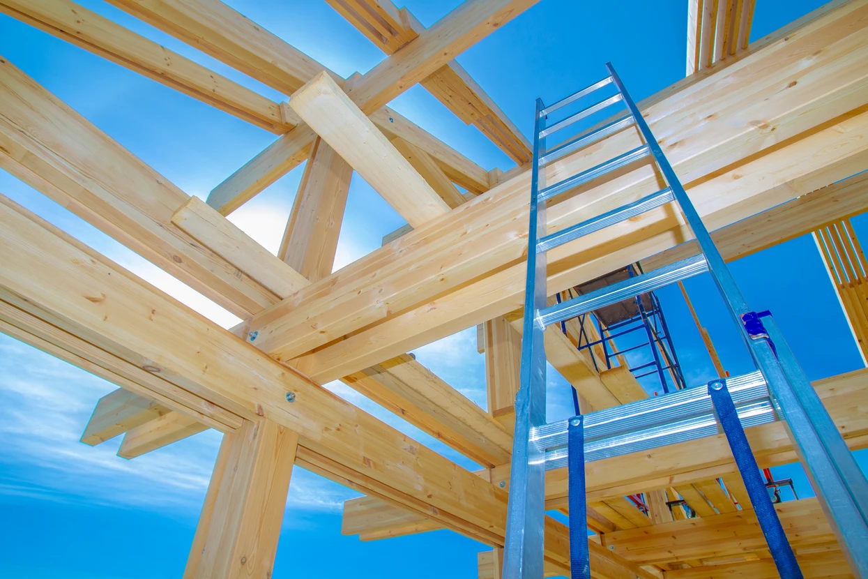 Chantier de construction en bois avec charpente traditionnelle en cours d'assemblage sous ciel bleu