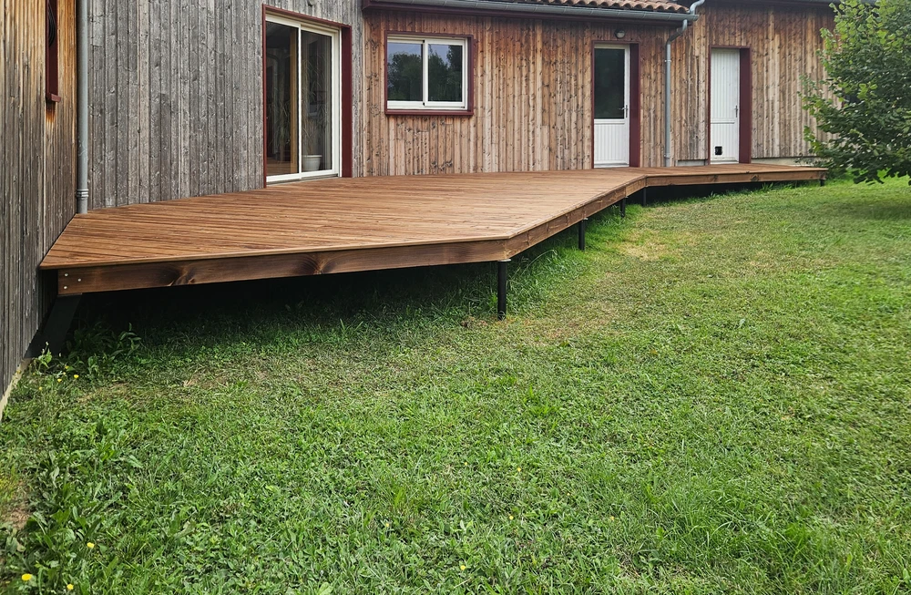 Terrasse extérieure en bois exotique avec planches alignées, structure surélevée sur pilotis