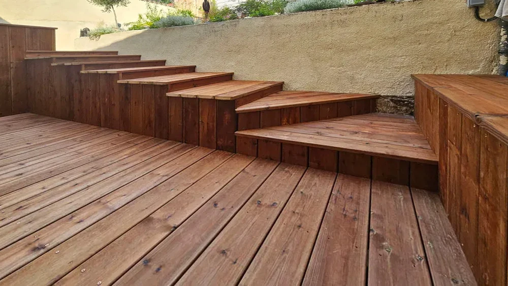 Escalier extérieur en bois avec terrasse, construction sur plusieurs niveaux entre murs crépis beiges